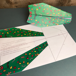 A Christmas themed paper plane making kit with a made up paper plane