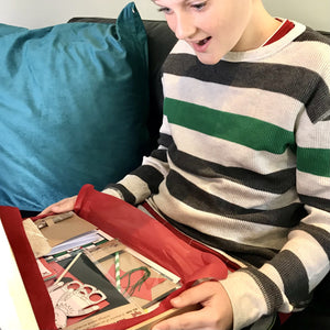 A little boy excited to open a box full of eco friendly Christmas Eve crafts and activities.