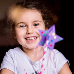 Little girl holding a paper craft wand at a birthday party